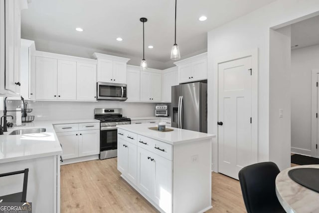 kitchen featuring white cabinets, appliances with stainless steel finishes, light wood-style floors, and a sink