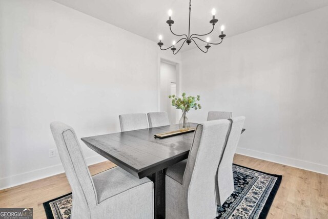 dining room featuring baseboards, light wood-type flooring, and a chandelier