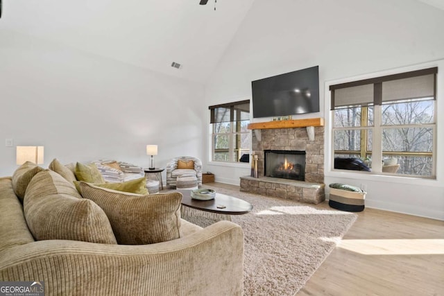 living area featuring visible vents, baseboards, a fireplace, wood finished floors, and high vaulted ceiling