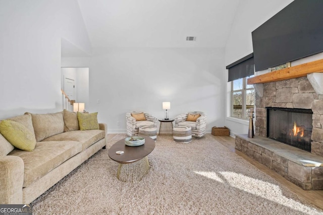 living area featuring visible vents, baseboards, a fireplace, wood finished floors, and high vaulted ceiling