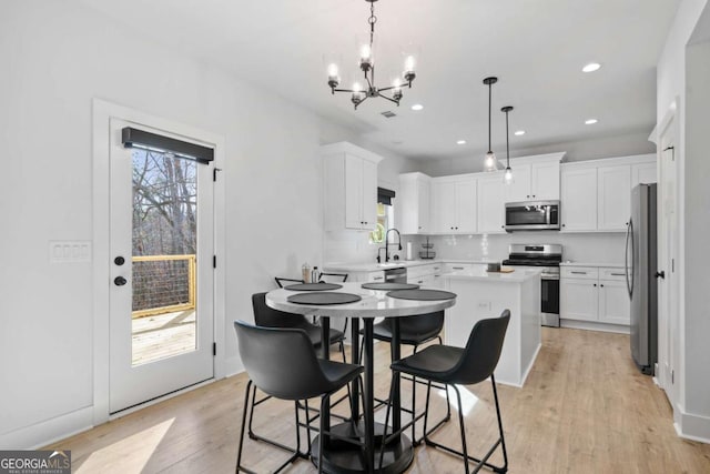 kitchen with a sink, light wood-style floors, white cabinetry, and stainless steel appliances