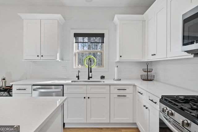 kitchen with light countertops, decorative backsplash, stainless steel appliances, white cabinetry, and a sink