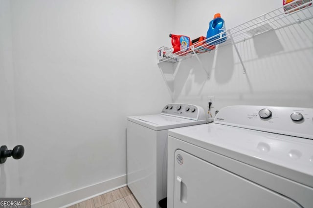 laundry room with light wood finished floors, baseboards, laundry area, and washing machine and clothes dryer