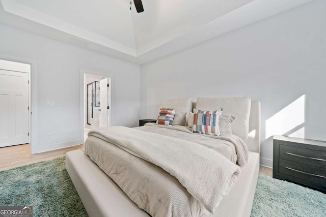 bedroom featuring ceiling fan, wood finished floors, baseboards, and connected bathroom