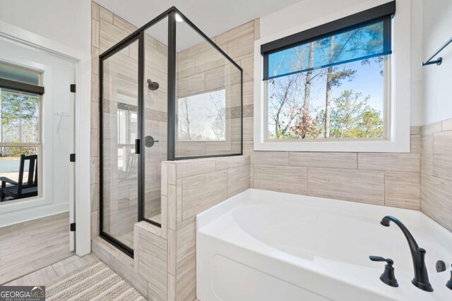 full bathroom featuring plenty of natural light, a bath, and a shower stall