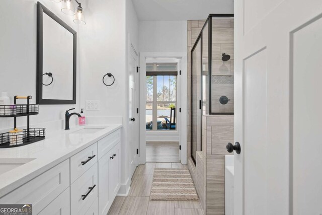 bathroom featuring a shower stall, double vanity, and a sink