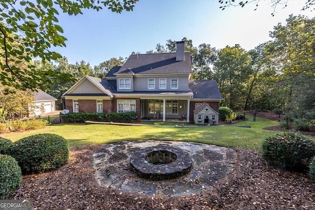 back of house with a yard and a fire pit