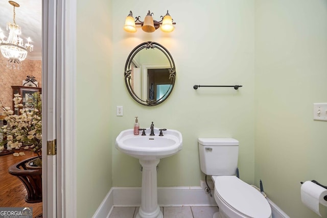 bathroom with toilet, tile patterned floors, and an inviting chandelier