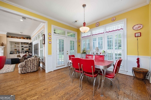 dining area with wood-type flooring, built in shelves, crown molding, and french doors