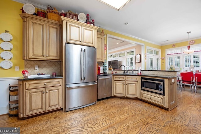 kitchen featuring kitchen peninsula, decorative backsplash, sink, crown molding, and appliances with stainless steel finishes