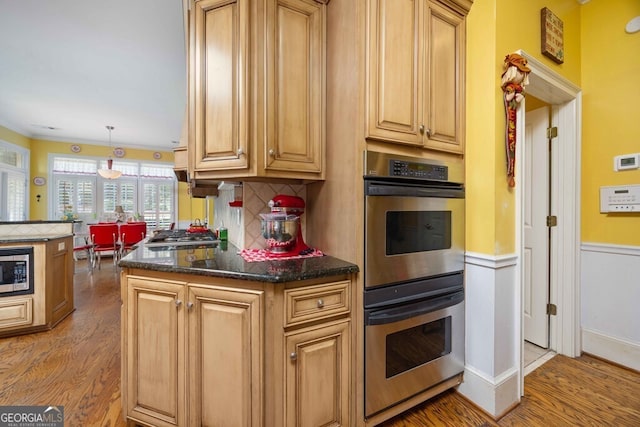 kitchen featuring backsplash, light hardwood / wood-style floors, pendant lighting, kitchen peninsula, and stainless steel appliances