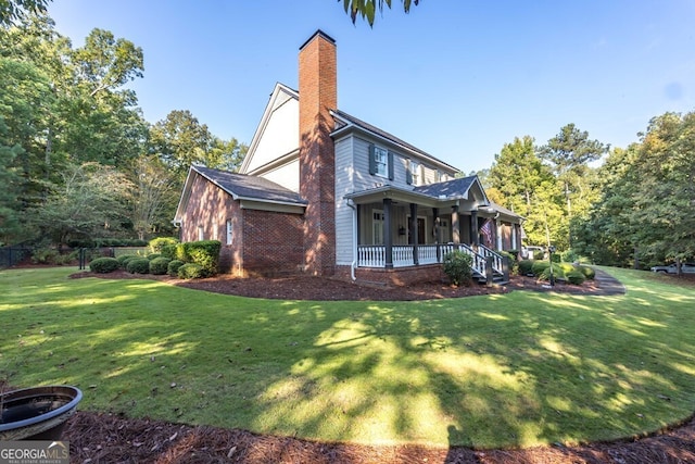 view of side of property featuring covered porch and a yard