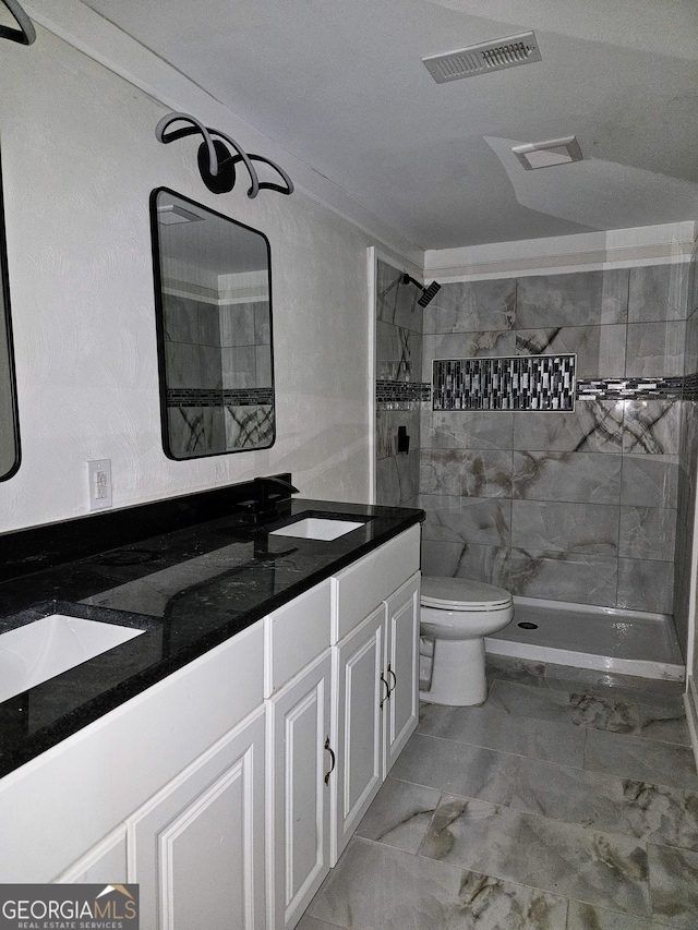 bathroom with toilet, vanity, and tiled shower