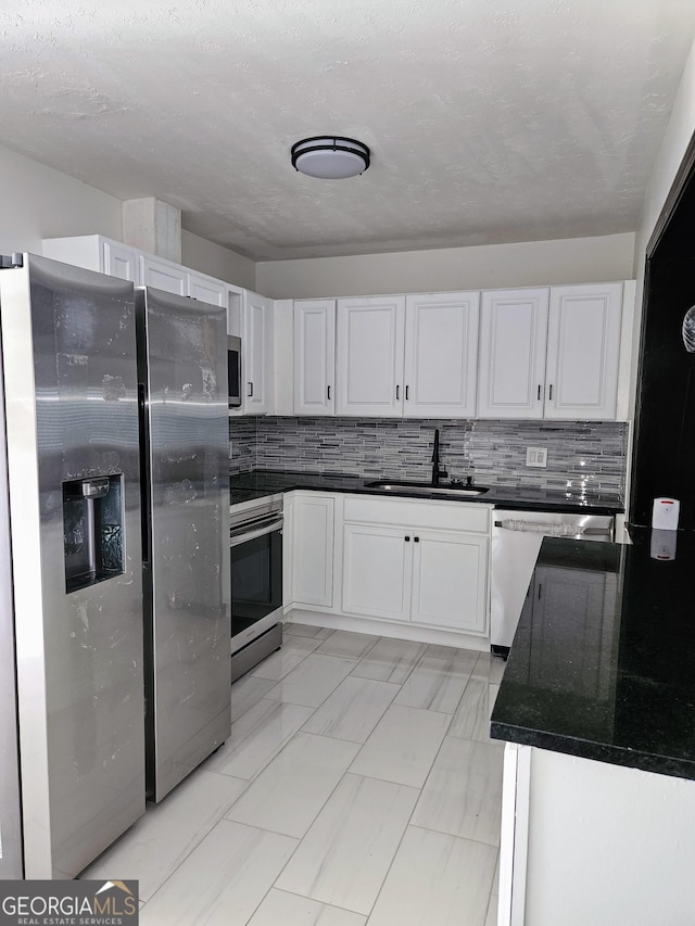 kitchen featuring stainless steel appliances, backsplash, white cabinetry, and sink