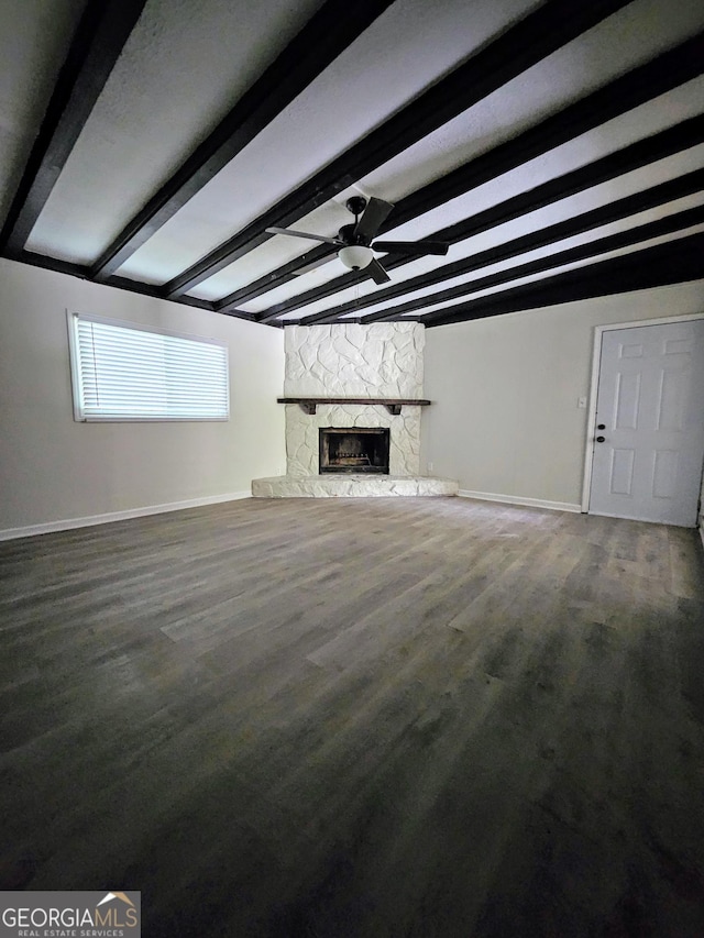 unfurnished living room featuring hardwood / wood-style flooring, ceiling fan, beam ceiling, and a stone fireplace