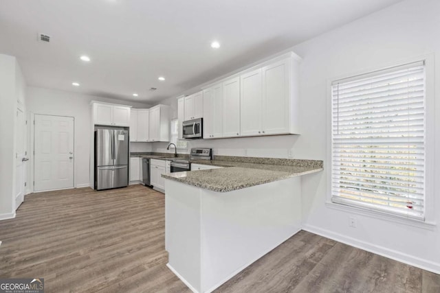 kitchen with sink, white cabinets, appliances with stainless steel finishes, and kitchen peninsula