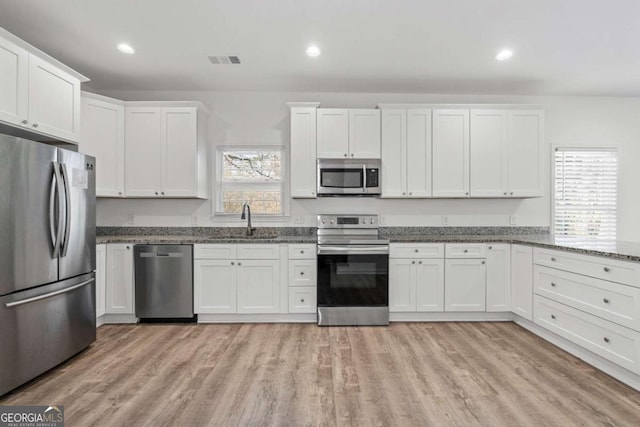 kitchen featuring white cabinets, appliances with stainless steel finishes, sink, and dark stone countertops