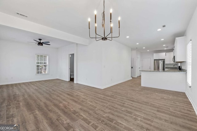 unfurnished living room featuring sink, ceiling fan with notable chandelier, and light hardwood / wood-style floors