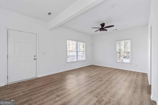 spare room with ceiling fan, a healthy amount of sunlight, beamed ceiling, and light hardwood / wood-style floors