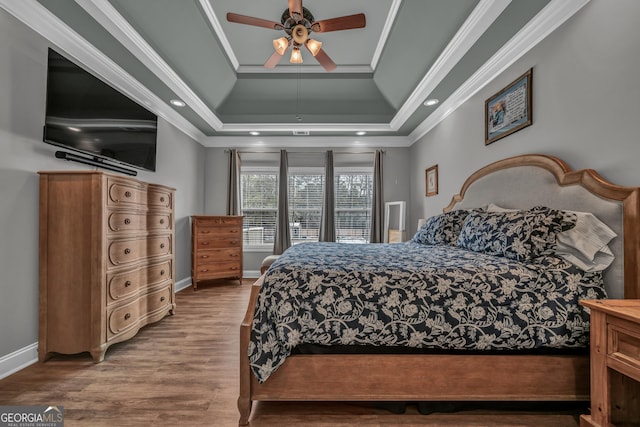 bedroom featuring crown molding, ceiling fan, a raised ceiling, and hardwood / wood-style flooring