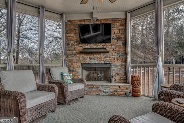 sunroom / solarium featuring a stone fireplace and ceiling fan