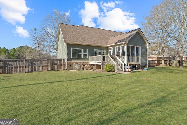 back of house with a wooden deck, a lawn, and a sunroom