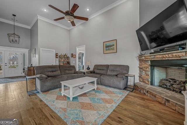 living room with crown molding, a fireplace, hardwood / wood-style floors, and a high ceiling