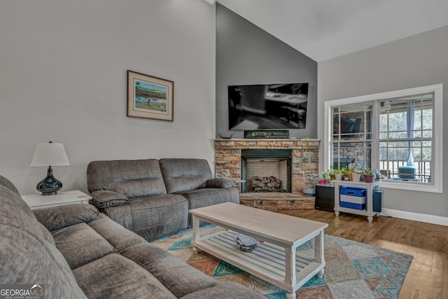 living room featuring lofted ceiling, hardwood / wood-style floors, and a stone fireplace