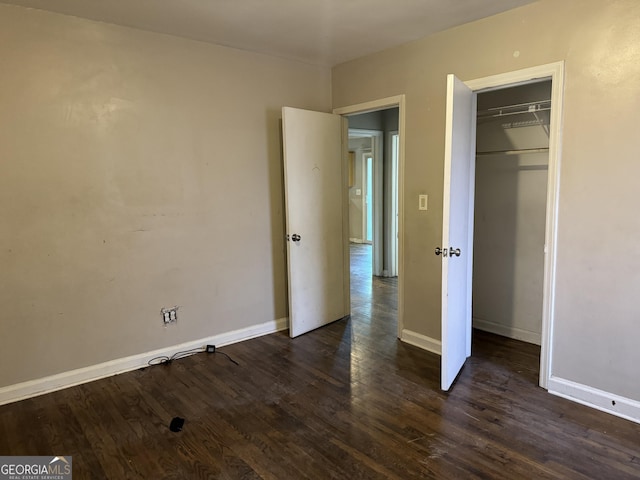 unfurnished bedroom with dark hardwood / wood-style flooring and a closet