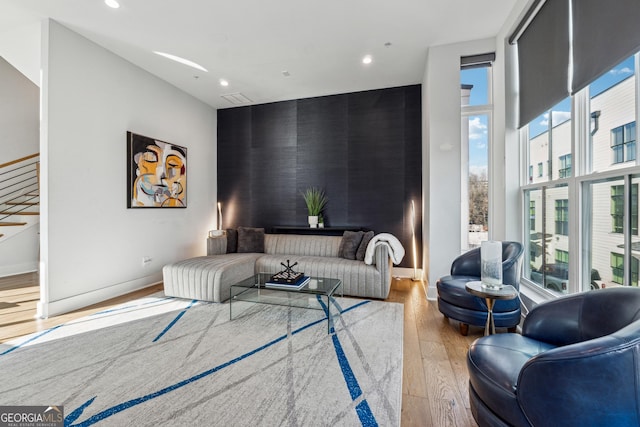 living room with light wood-style flooring, an accent wall, baseboards, and recessed lighting