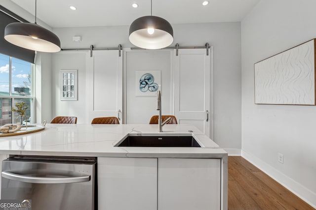 kitchen featuring a barn door, a sink, white cabinets, dishwasher, and pendant lighting