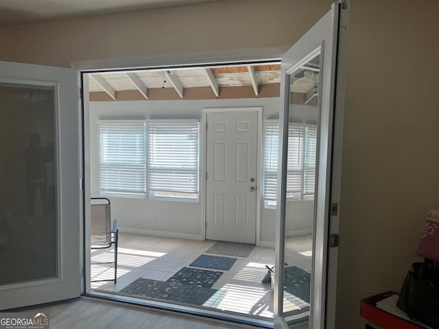 entrance foyer featuring beam ceiling, baseboards, and light tile patterned floors