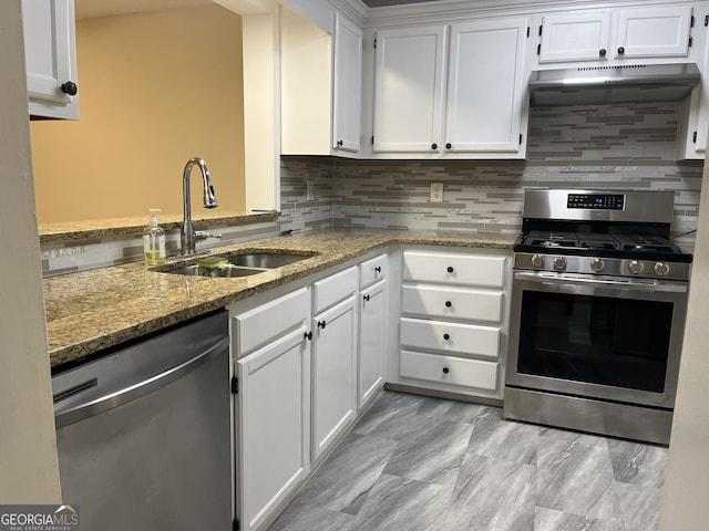 kitchen with appliances with stainless steel finishes, a sink, white cabinetry, and light stone countertops