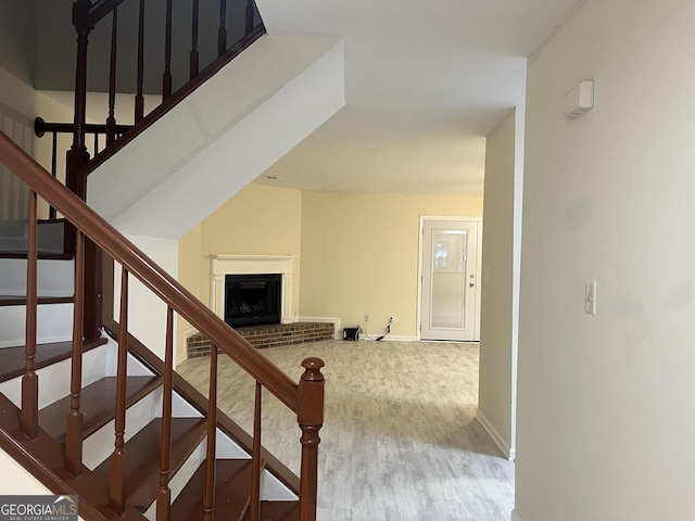 stairway with a fireplace, wood finished floors, and baseboards