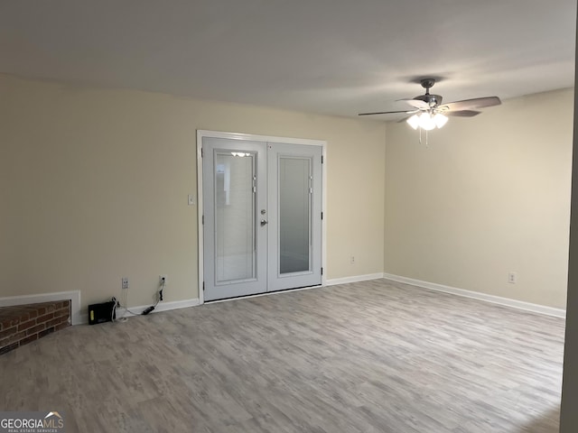 unfurnished room with a ceiling fan, baseboards, wood finished floors, and french doors