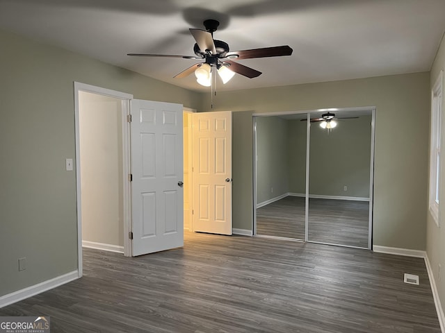 unfurnished bedroom with dark wood-style floors, visible vents, baseboards, and a closet