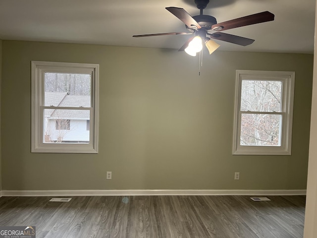 spare room featuring dark wood-style floors, visible vents, baseboards, and ceiling fan