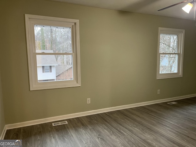 unfurnished room featuring dark wood-style flooring, visible vents, ceiling fan, and baseboards