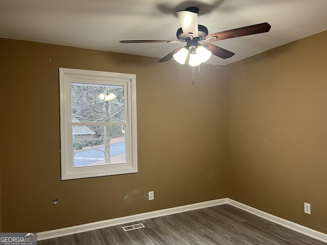 empty room featuring a ceiling fan, dark wood-style flooring, visible vents, and baseboards