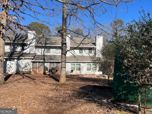 rear view of house featuring a sunroom and a chimney