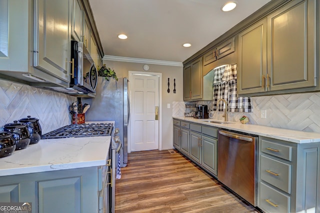 kitchen with tasteful backsplash, appliances with stainless steel finishes, sink, and crown molding