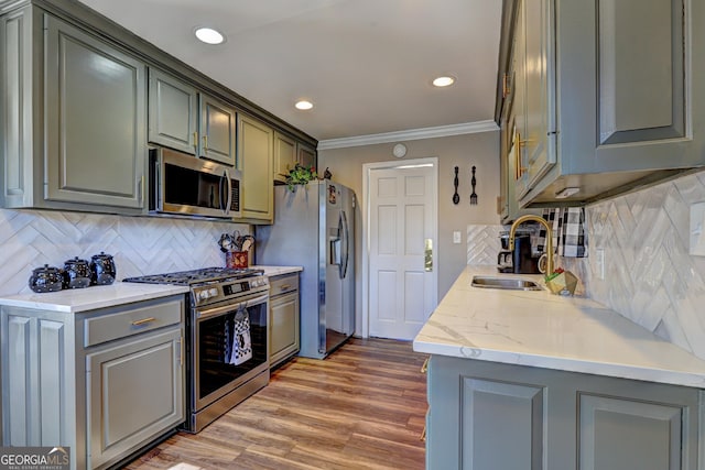 kitchen featuring tasteful backsplash, hardwood / wood-style floors, sink, crown molding, and stainless steel appliances