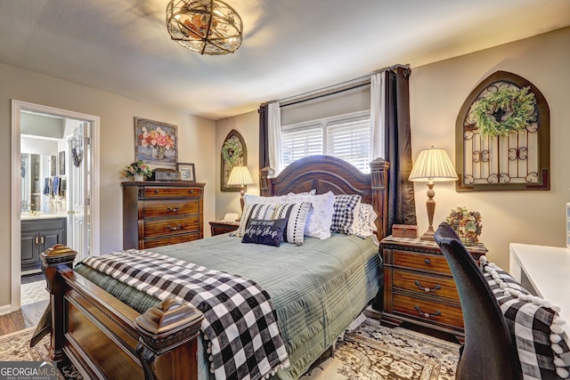 bedroom with ensuite bathroom and light hardwood / wood-style flooring