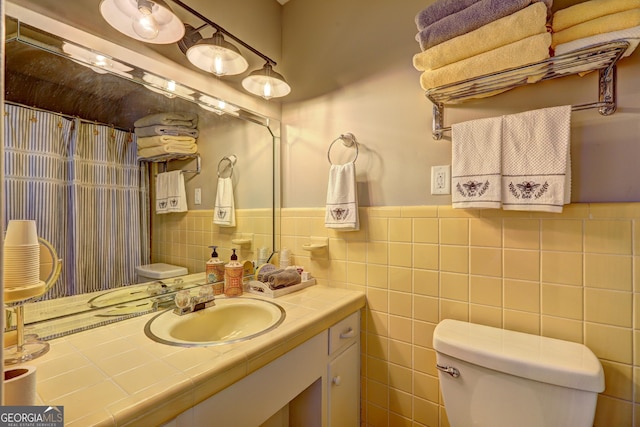 bathroom featuring tile walls, toilet, and vanity