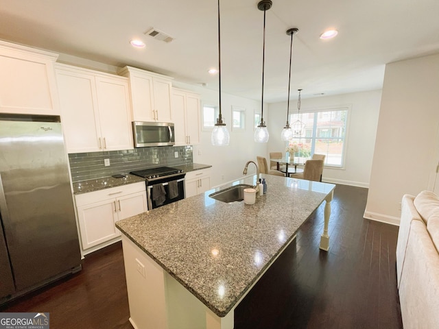 kitchen featuring a center island with sink, appliances with stainless steel finishes, decorative light fixtures, white cabinets, and sink