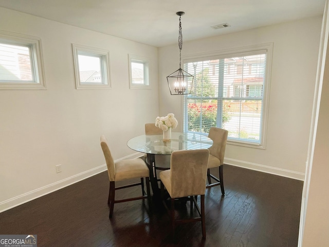 dining space featuring dark hardwood / wood-style floors and an inviting chandelier