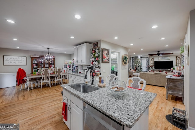 kitchen with white cabinetry, sink, dishwasher, and an island with sink