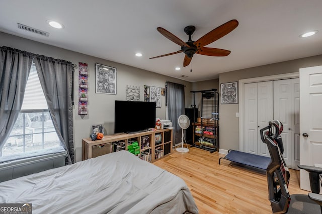 bedroom featuring ceiling fan, a closet, wood-type flooring, and multiple windows