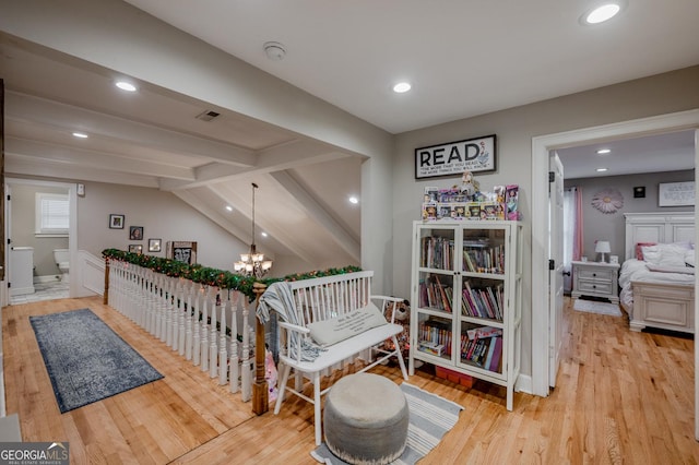 hallway featuring lofted ceiling with beams, light wood-type flooring, and an inviting chandelier