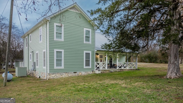 rear view of house with covered porch and a yard